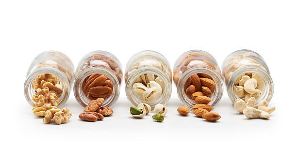 Picture of almonds, cashews, pistachios, walnuts and pecans in separate jars.
