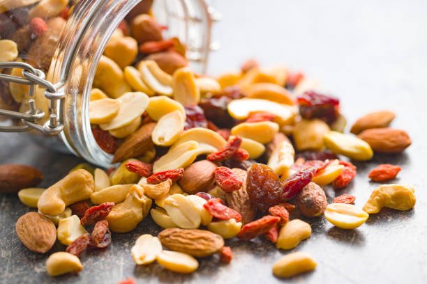 Picture of a mix of delicious nuts spilling out of a jar - it is difficult to separate the different nuts.